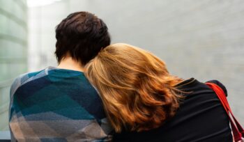 Young woman with head on a man's shoulders with backs to camera