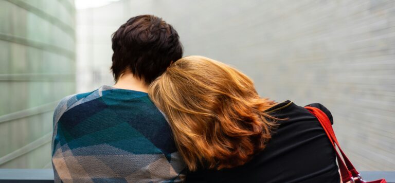 Young woman with head on a man's shoulders with backs to camera