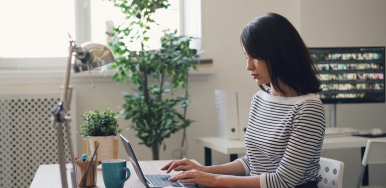 Young Asian woman using laptop in minimalistic office