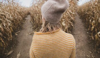 Woman in wool had deciding which path to take in a cornfield