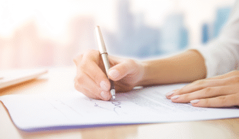 One Signature Divorce NYC – signing divorce papers with a single signature featuring a woman signing legal documents with a silver pen, illustrating an affordable divorce service in New York City.