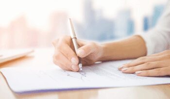 One Signature Divorce NYC – signing divorce papers with a single signature featuring a woman signing legal documents with a silver pen, illustrating an affordable divorce service in New York City.